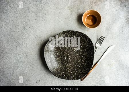 Minimalistic table setting with ceramic bowl and cutlery on concrete table Stock Photo