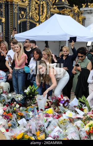 London, UK. 10th Sep, 2022. A lady leaves a floral tribute to Her Majesty Queen Elizabeth II at Buckingham Palace. Credit: Simon Ward/Alamy Live News Stock Photo