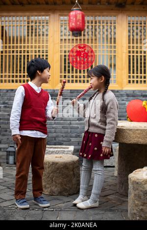 Happy Chinese sibling eating candied haws Stock Photo
