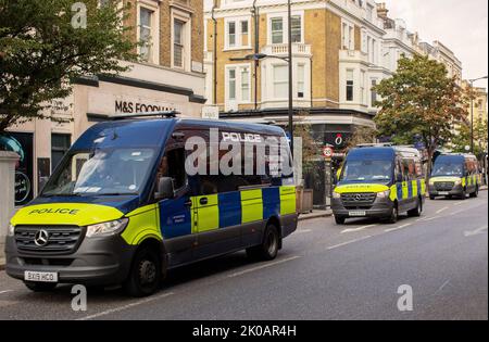 Three police vans from the Territorial Support Group driving down the Earls Court Road Stock Photo