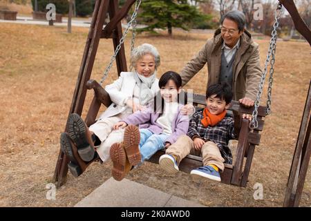 Happy Chinese family playing on a swing Stock Photo