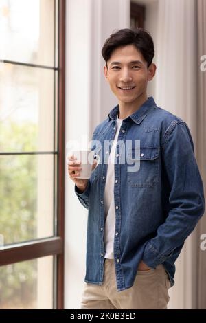 Happy young Chinese man holding coffee Stock Photo