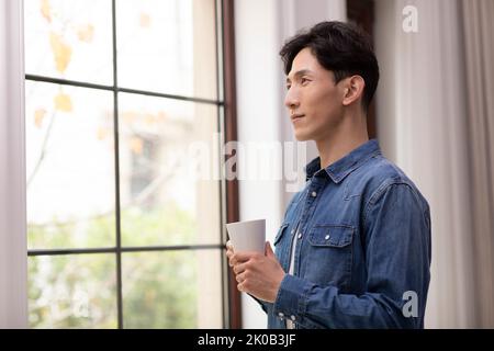 Happy young Chinese man holding coffee Stock Photo