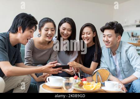 Young Chinese friends using smart phones on sofa Stock Photo