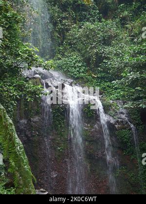 A small waterfall that flows between rocks in a tropical forest river in West Java, Indonesia Stock Photo