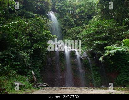 A small waterfall that flows between rocks in a tropical forest West Java, Indonesia Stock Photo