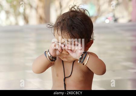 Close-up photo Portrait of Indian hindu Baby boy kid covering close his eyes with hands with with funny expression, Rajasthan India Stock Photo