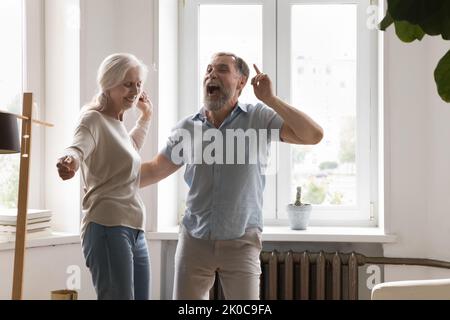 Joyful excited mature retired couple having fun at home party Stock Photo