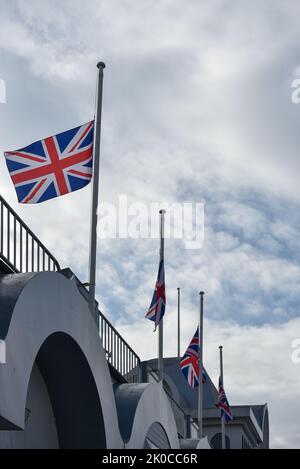 Union Jack flags flying at half mast as a gesture of respect for the death of Queen Elizabeth 2nd. These flags are on South Parade Pier in Portsmouth, Stock Photo