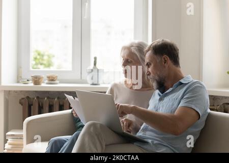 Engaged serious mature married couple doing paperwork job at home Stock Photo