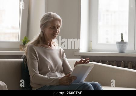 Happy retired tablet user lady using online virtual app Stock Photo