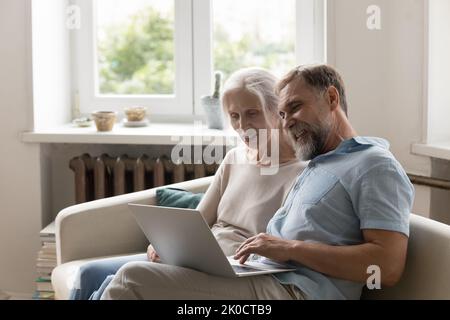 Cheerful older 60s married couple sitting on home sofa Stock Photo