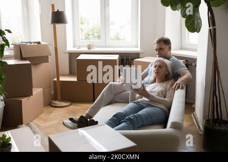 Relaxed mature couple of homeowners using graphic app on tablet Stock Photo
