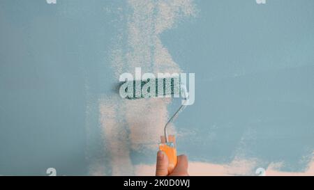 Hand painting the wall with decorator roller and painting walls Stock Photo