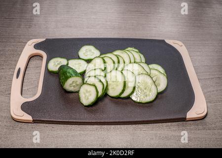 Sliced fresh cucumber for salad on a cutting board. Healthy vegetarian food. Ripe vegetables. Stock Photo