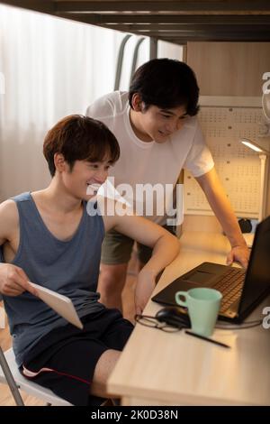 Young Chinese university students using laptop in dormitory Stock Photo