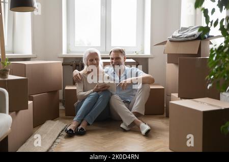Happy old couple of new homeowners sitting on heating floor Stock Photo