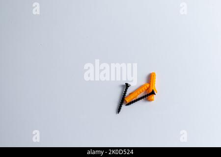 Black screw with plastic dowels plugs on isolated white background Stock Photo