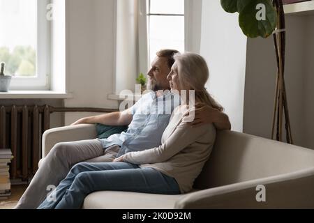 Happy mature retired family couple sitting on sofa indoors Stock Photo