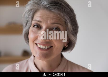 Facial portrait of happy mature retired woman looking at camera Stock Photo