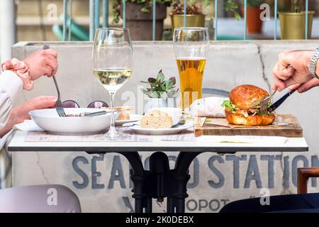 White wine, beer and tasty dishes in outdoor restaurant. Couple having lunch or dinner in sunny summer day in sidewalk cafe. Friends having a meal out Stock Photo