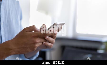 Young business man standing indoors, holding mobile phone Stock Photo