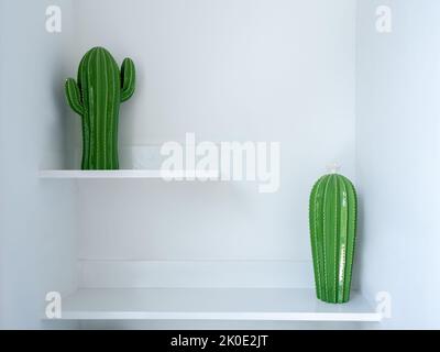 Two green ceramic cactus doll model decoration on two steps of white shelf. Home decor with fake plant object. Stock Photo