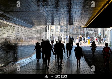 Amsterdam, Netherlands - August 2022: Silhouettes of people walking through a tunnel under the city's railway station