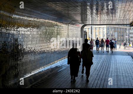 Amsterdam, Netherlands - August 2022: Silhouettes of people walking through a tunnel under the city's railway station