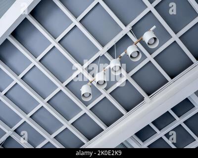 five spotlight hanging  in cafe. Modern ceiling lamps set under the stylish construction building in living room in the white house. Stretch ceiling w Stock Photo