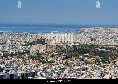 Athens, Greece - May 2022: Aerial view of Athens with The Parthenon. In the background is the coastal port of Piraeus Stock Photo