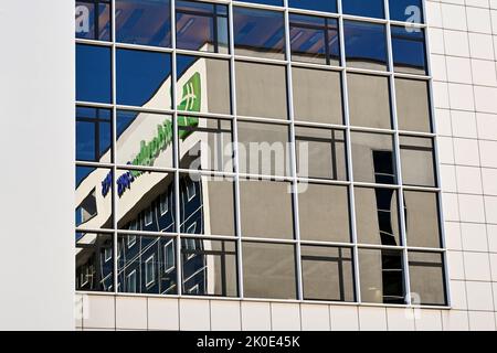 Antwerp, Belgium - August 2022: Sign on top of a Holiday Inn Express hotel reflected in the glass panels of a nearby building. No people. Stock Photo