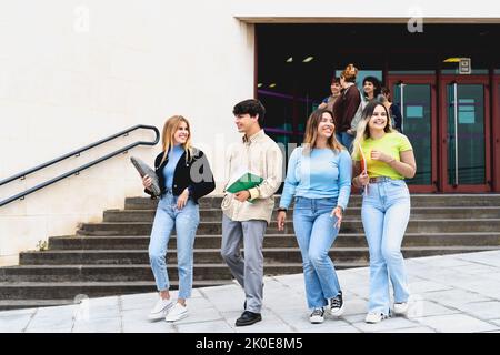 Young diverse students leaving university after lesson - Youth and education concept Stock Photo