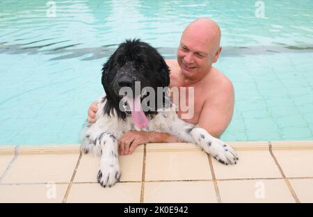 Pattensen, Germany. 11th Sep, 2022. Newfoundland Georg and his owner Heino Kook swim together in the water at the Pattensen outdoor pool in the Hannover region. At the end of the season, many outdoor pools open for four-legged guests: On the last day of opening, dogs are allowed to jump into the cool wet with their owners. Credit: Julian Stratenschulte/dpa/Alamy Live News Stock Photo