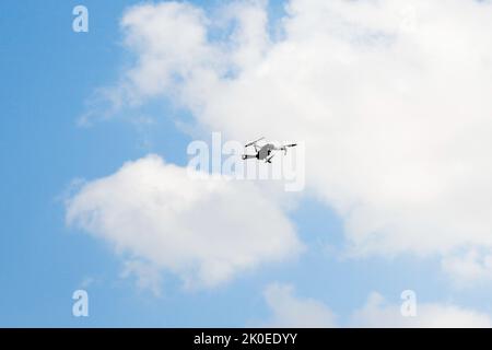 Defocus war drone. Drone flying in a blue sky. The black army unmanned aerial vehicle with four propellers and blades is on the blue sky background. W Stock Photo