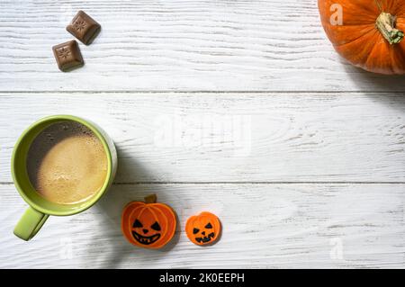 Halloween and coffee theme, orange pumpkin, sweets and cup on white table, top view. Holiday food on wood planks background with space, flat lay. Part Stock Photo