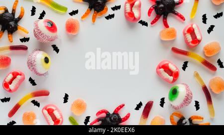 Close-up bright jelly candies,spiders,eyes,jaws,worms and bats,on white background,top view,flat lay,copy space.Decor concept for Halloween party,holi Stock Photo