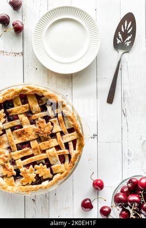 Top down view of a freshly baked lattice cherry pie with plates for serving. Stock Photo