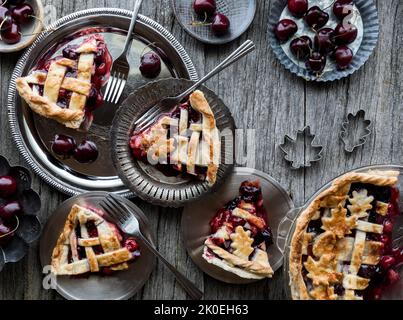 Slices of homemade lattice cherry pie on metal plates, ready for eating. Stock Photo