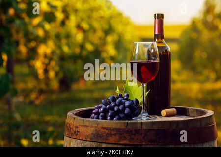red wine in glass and grape on wooden barrel with vineyard Stock Photo