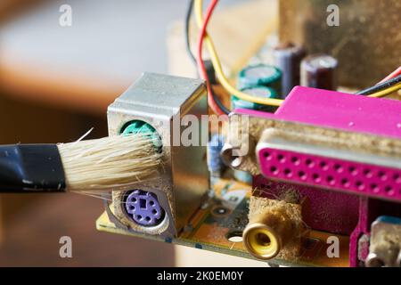 Brush cleaning an old computer board from dust and dirt. Close-up. Stock Photo