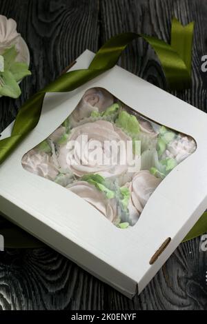 Zephyr flowers. Zephyr in a cardboard box. Near samples of marshmallows. Tape for tying the box. On pine boards. Stock Photo