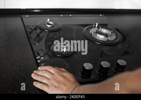 Installation of a gas three-burner built-in stove in a black countertop. Kitchen interier. Stock Photo