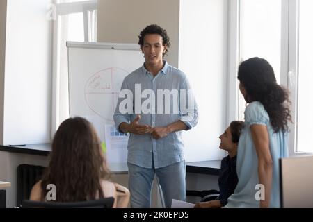 Serious engaged Latin presenter guy speaking before diverse audience Stock Photo