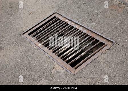 A rusty storm grate in an asphalt road Stock Photo
