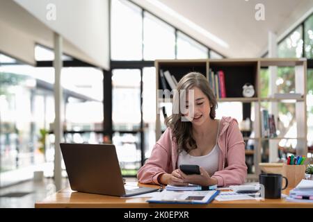 Attractive asian woman using mobile phone during checking an email or social media on internet. accounting financial concept. Stock Photo
