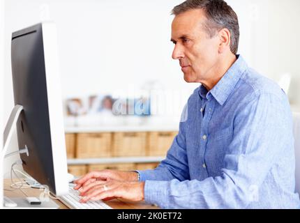 Mature man working on computer at home. Closeup portrait of a mature man working on computer at home. Stock Photo