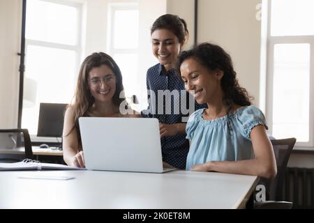 Happy successful diverse team of three employees women using laptop Stock Photo