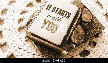 It starts with you text on notebook, glasses and pen. Personal motivational business and career concept. Stock Photo