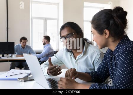 Two Indian employees collaborating on project, sitting at work table Stock Photo